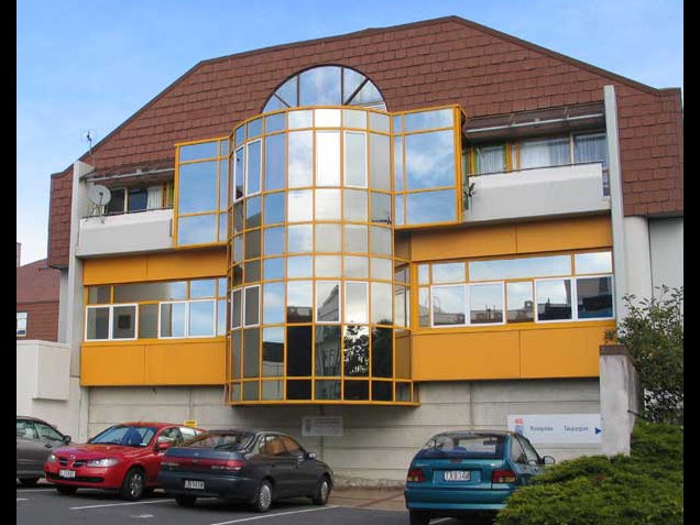 Te Papa's Tory St building, photograph by Chris Paulin. Te Papa A white and yellow building with cars parked in front of it.
