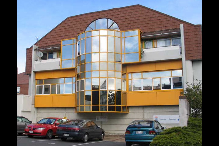 A white and yellow building with cars parked in front of it.