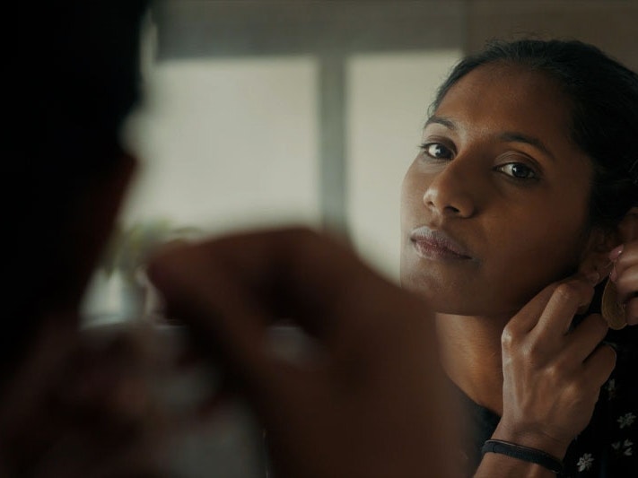 Still from ‘Healing doesn’t just happen in one mode’: reconsidering what ‘therapy’ looks like, 2023. Photo by Julie Zhu Photo of a woman looking into mirror, putting on an earring.