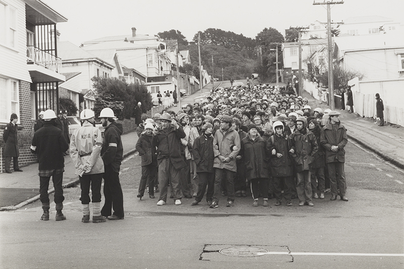 People standing in a group ready for a protest. There are police standing to the left of them.