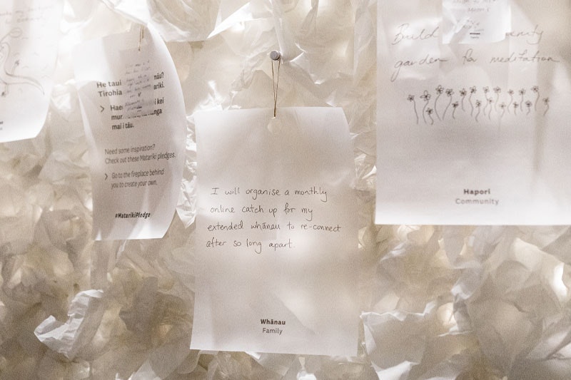 Photograph of a note pinned to a wall. The wall is decorated with white crumpled tissue paper to resemble clouds. The note says: I will organise a monthly online catch up for my extended whānau (family) to re-connect after so long apart