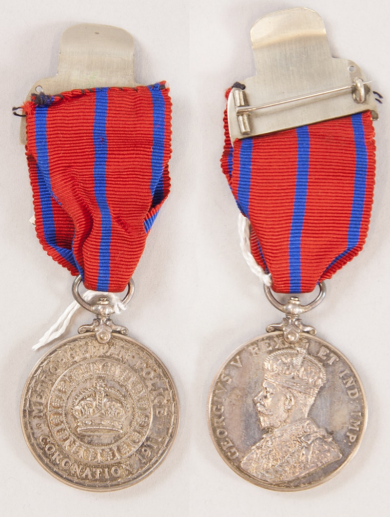 A front and back view of a medal with a King's profile on one side and a crown on another.