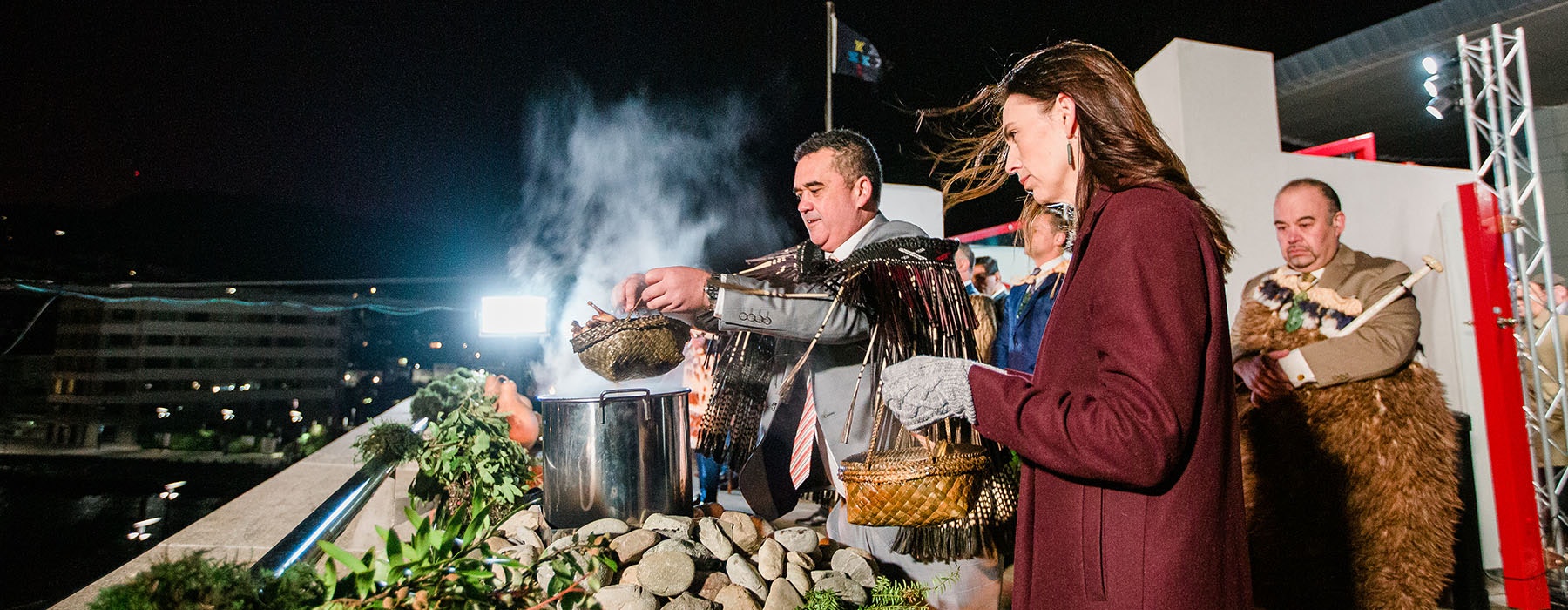 Rangi Matamua lifts the lid from the food pot to release steam into the sky, with then-Prime Minister Jacinda Ardern looking on