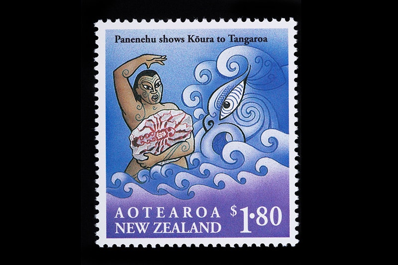 A stamp with a man on it holding a stone with the image of a crayfish on it. There's a taniwha or stylised dragon in the background.