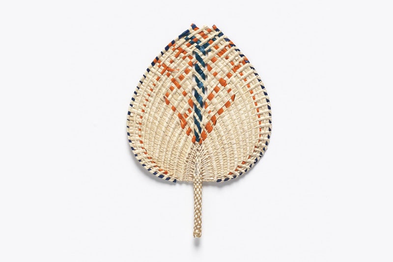 Fan made of coconut and pandanus leaves, featuring an orange and blue pattern woven throughout