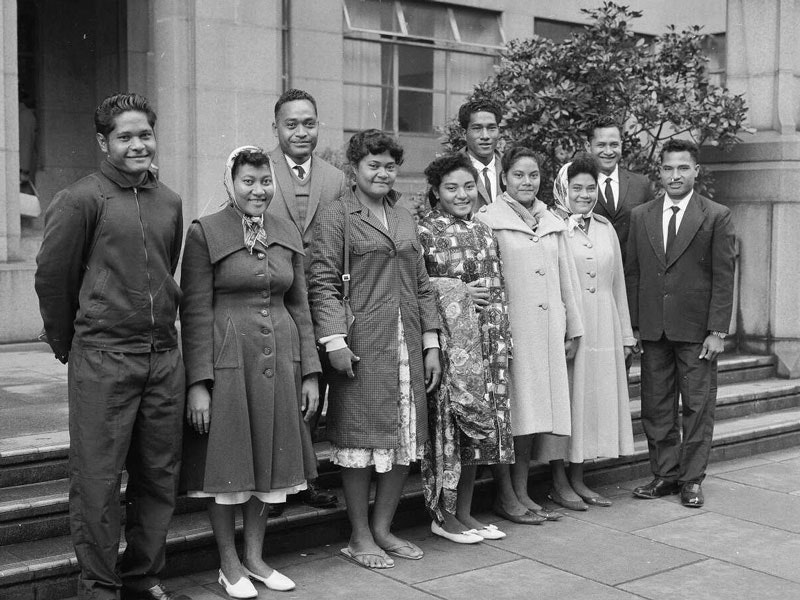 A black and white photo of a group of adults standing on some steps smiling