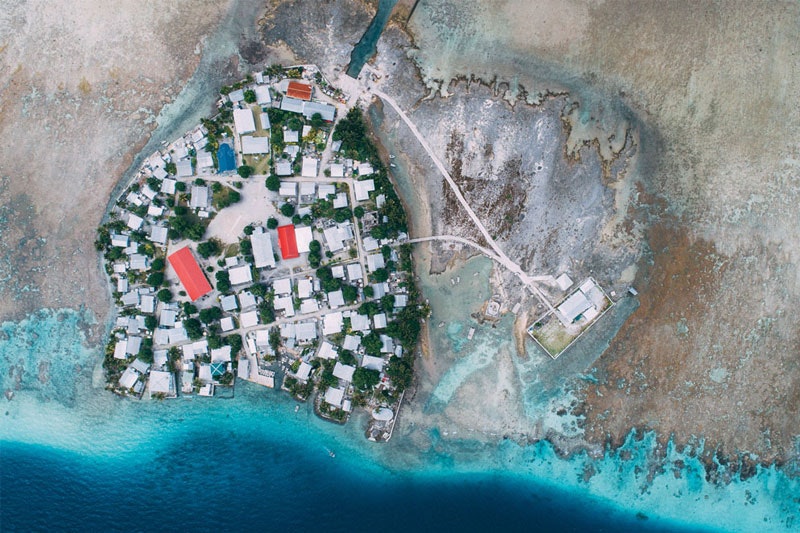 Aerial photo of an island showing dense housing, with the sea level around the island low