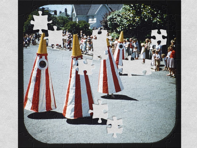 Hay’s procession, Christchurch, colour transparencies, FR Lamb; photographer; 1956-1957. Te Papa (CT.058924) Four people in cone costumes in a parade. Many people lining the street in the background