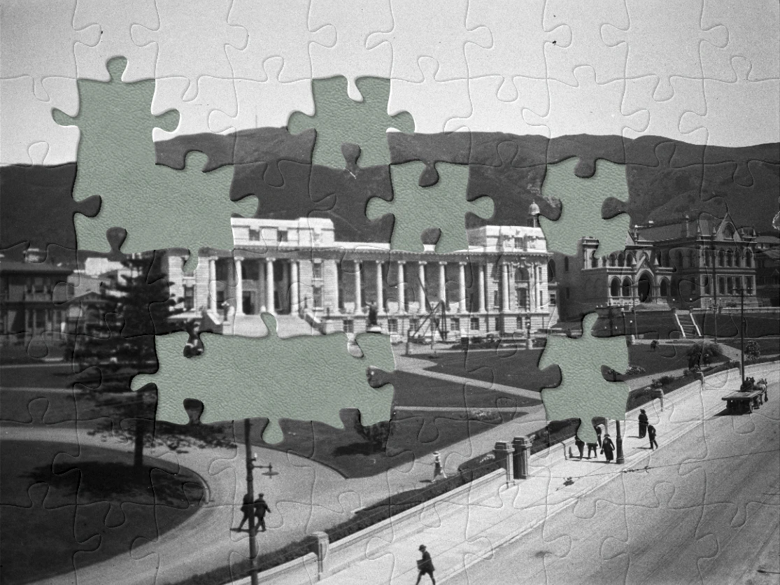 A black and white photo of a large building with very tidy lawns in front of it and jigsaw pieces 'cut' out of it