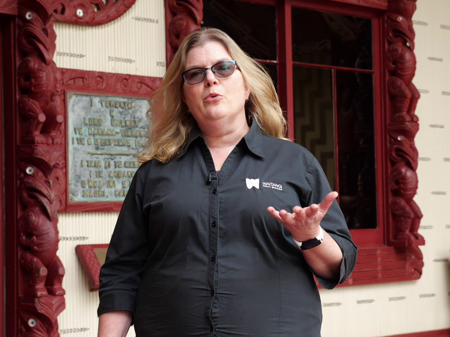 A woman standing in front of a carved house