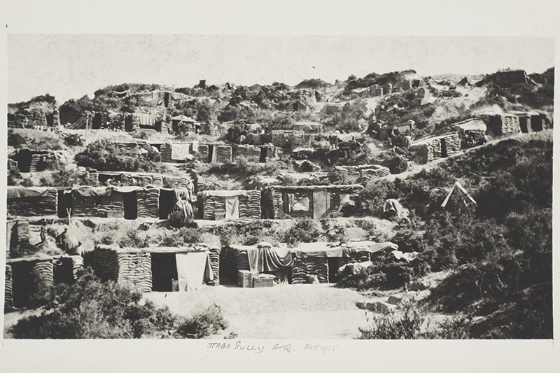 A black and white photo of Army huts on the side of a mountain.