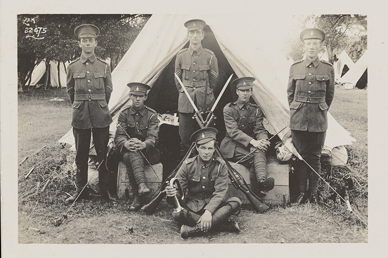 Several soldiers in uniform posing for the camera next to a tent.