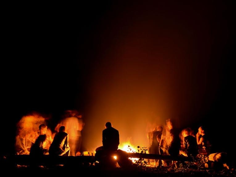A group of people sitting around a fire at night