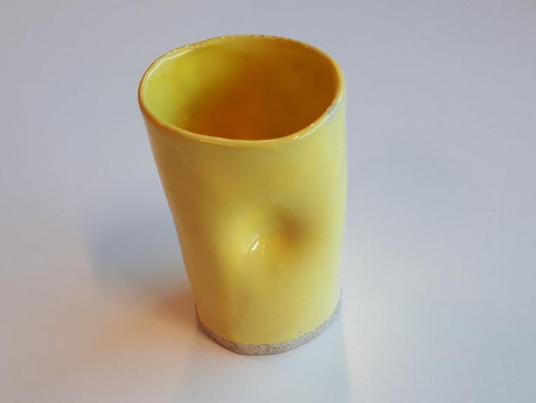 Yellow ceramic cup with a dent in it