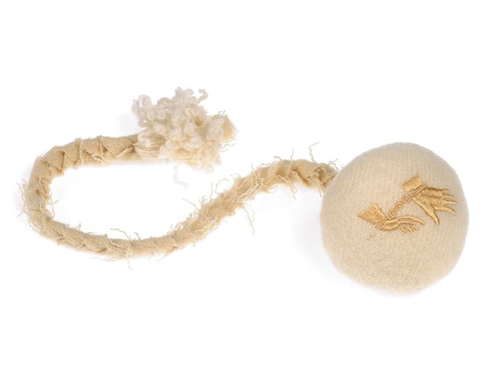 He poi manu, by Ngahina Hohaia, 2012. Recycled woollen blanket, calico, embroidery cottons. Gift of Teina Davidson, 2012. Te Papa (GH017810) A round ball wrapped in a blanket material and a plaited cord attached. The ball has two gold hands on it with the wrists in chains.