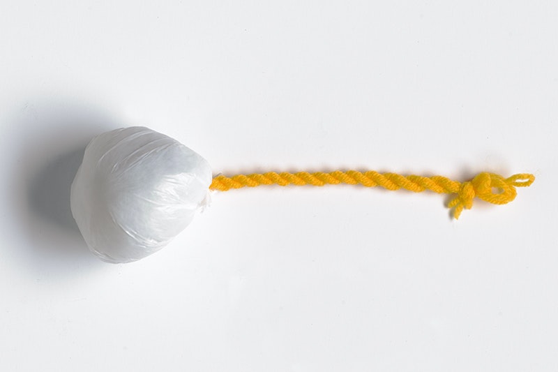 A round ball made of polyethylene with a wool and polyester cord attached to it.
