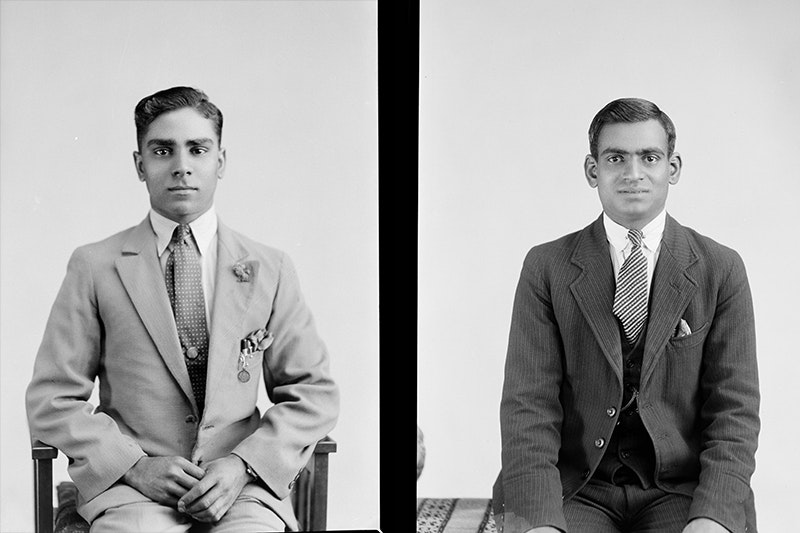 a split black and white image of two sitting men posing for a studio photograph.