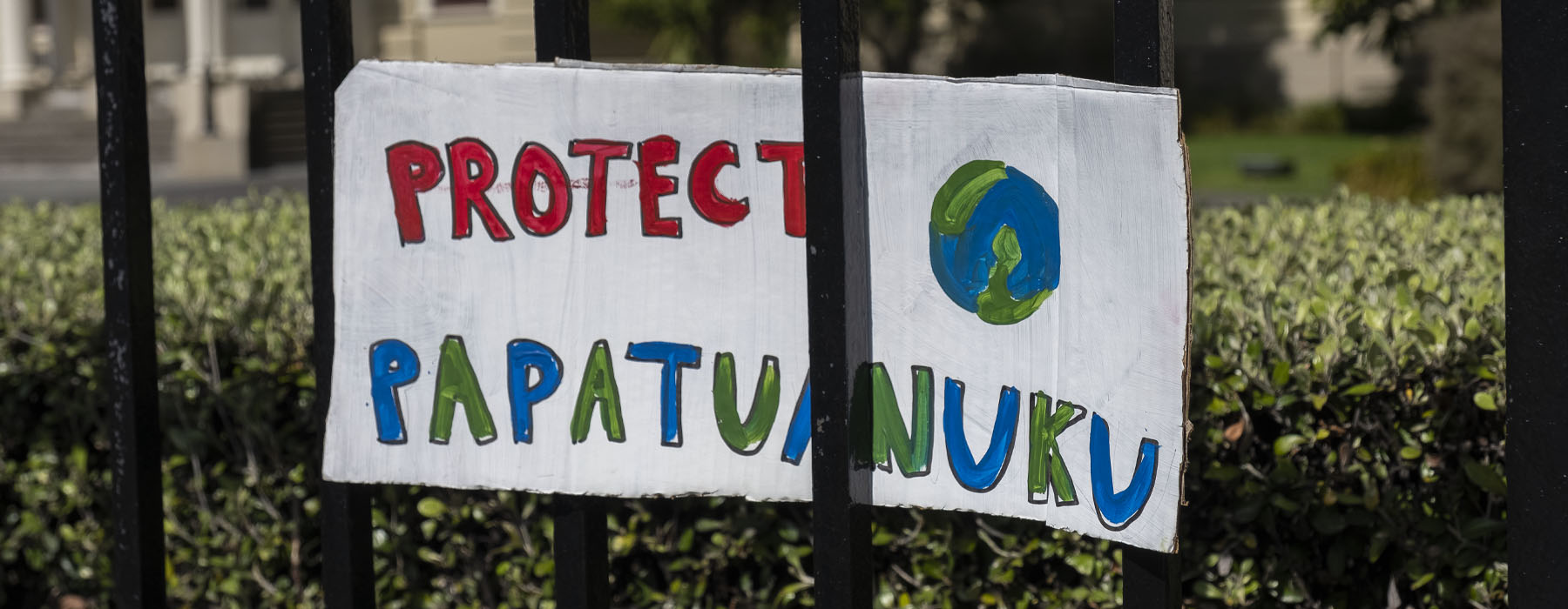 A sign on a fence with a picture of the Earth and the message "Protect Papatuanuku"