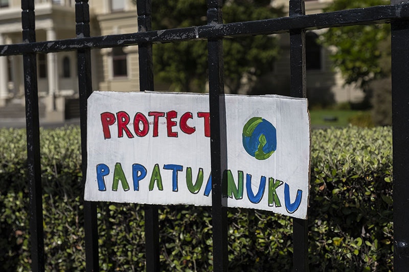 A sign on a fence with a picture of the Earth and the message "Protect Papatuanuku"