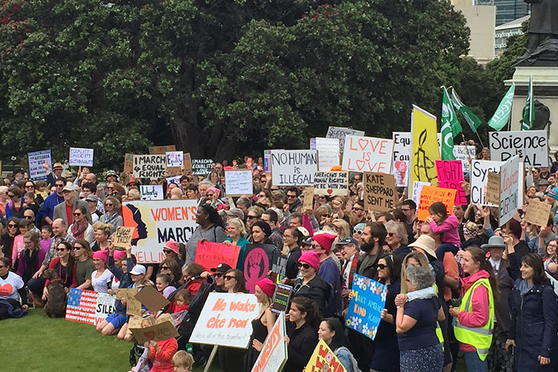 Photo of hundreds of people gathered on Parliament grounds, carrying many protest signs