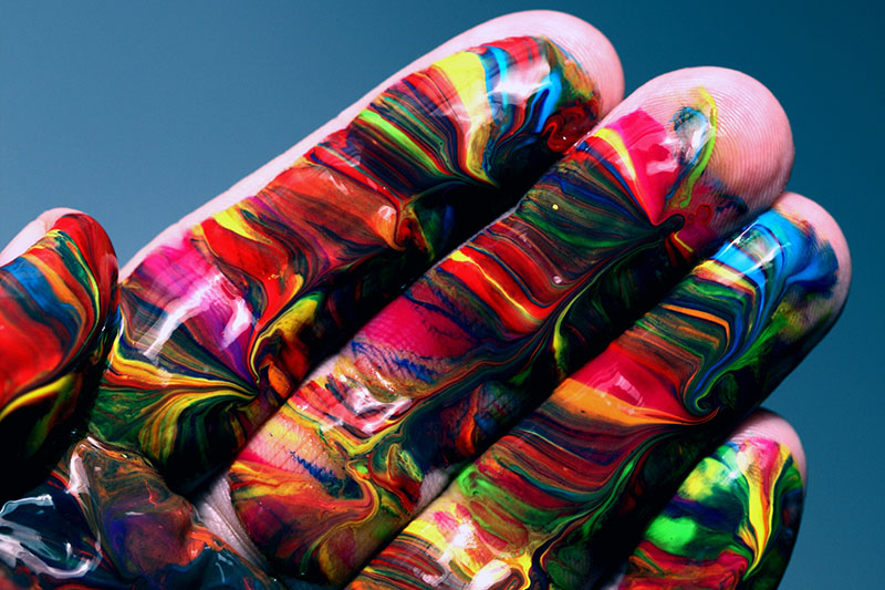 Close-up photo of a hand with multicoloured paints smeared across it