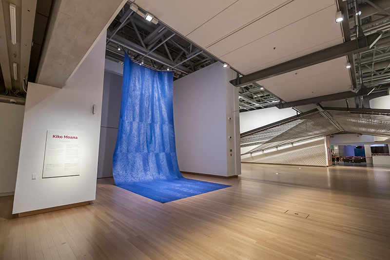 ‘Kiko Moana’ on display in Te Papa. A large sheet of blue tarpaulin hangs from the ceiling, and drapes onto the floor, resembling a waterfall