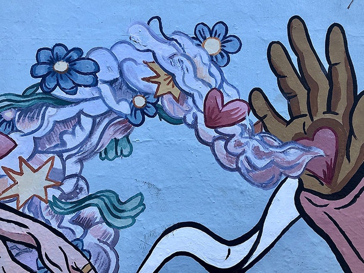 Mural, 2021. Photo by Katarzyna Pypla / Unsplash Paintings on a fence of an open hand held up with a love heart on the palm, emitting smoke filled with hearts and flowers