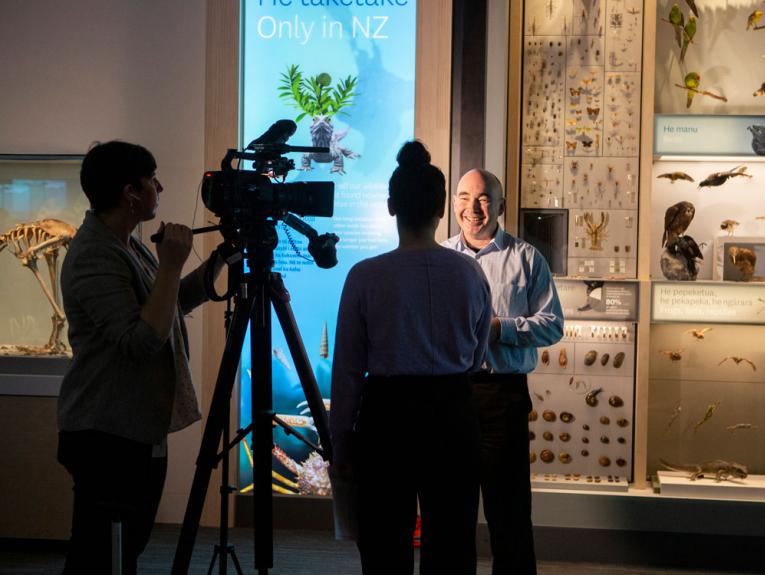 A man being interviewed in front of a large camera