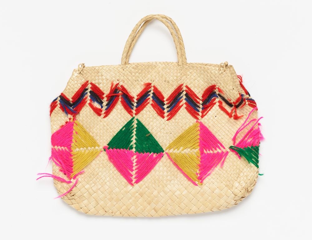 A woven basket with brightly coloured wool woven into patterns on the sides.