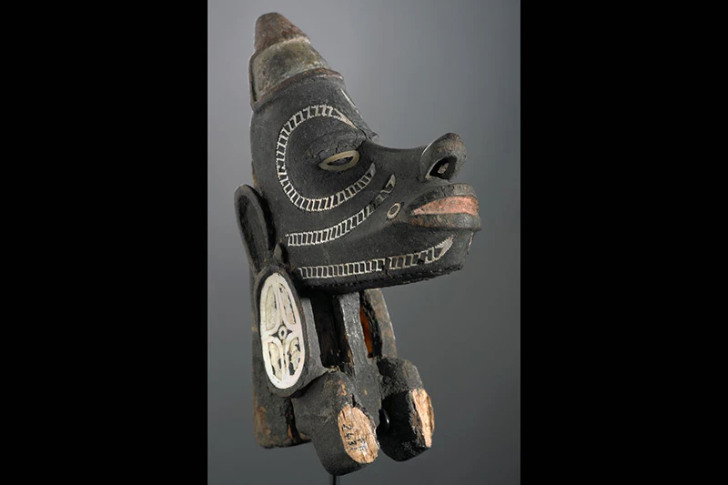 A carved wooden head figurine with inlaid shells