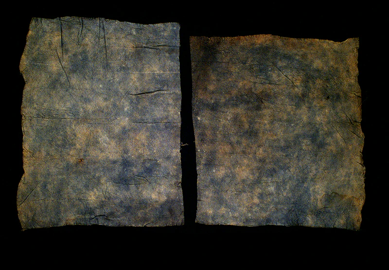 Two pieces of blue tapa cloth on a black background.