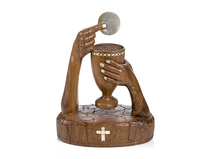 'The Great Elevation' chalice and host, by Reverend Francis Taupongi, 2006; Solomon Islands. Purchased 2007. Te Papa (FE011939) A carved wooden sculpture of two hands - one hand is holding a chalice and the other hand is holding a wafer over the chalice.
