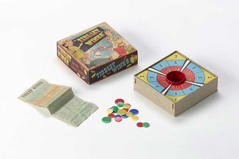 A game of tiddley winks with the box open and the pieces next to the box.