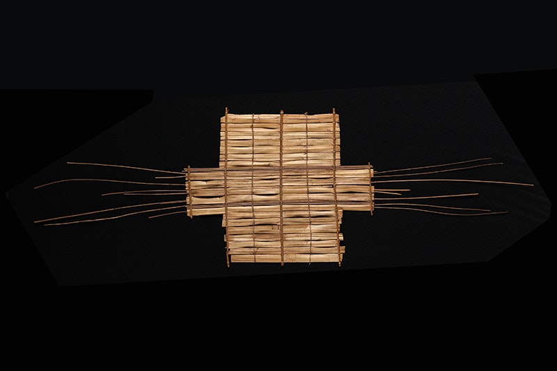 A rectangle woven from flax and wood with long sticks pointing out the sides like whiskers.