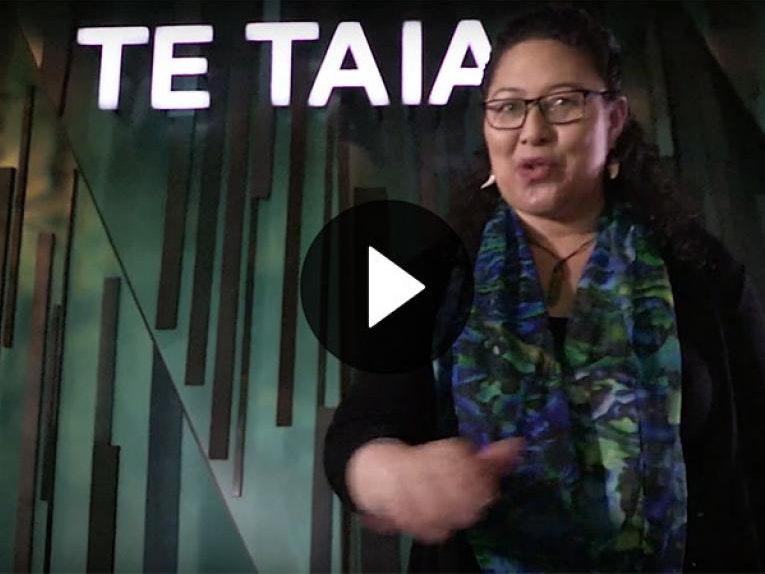 Te Taiao | Nature tour in te reo Māori (800wide) Screenshot of video. A woman stands at the entrance to Te Taiao | Nature talking to the camera