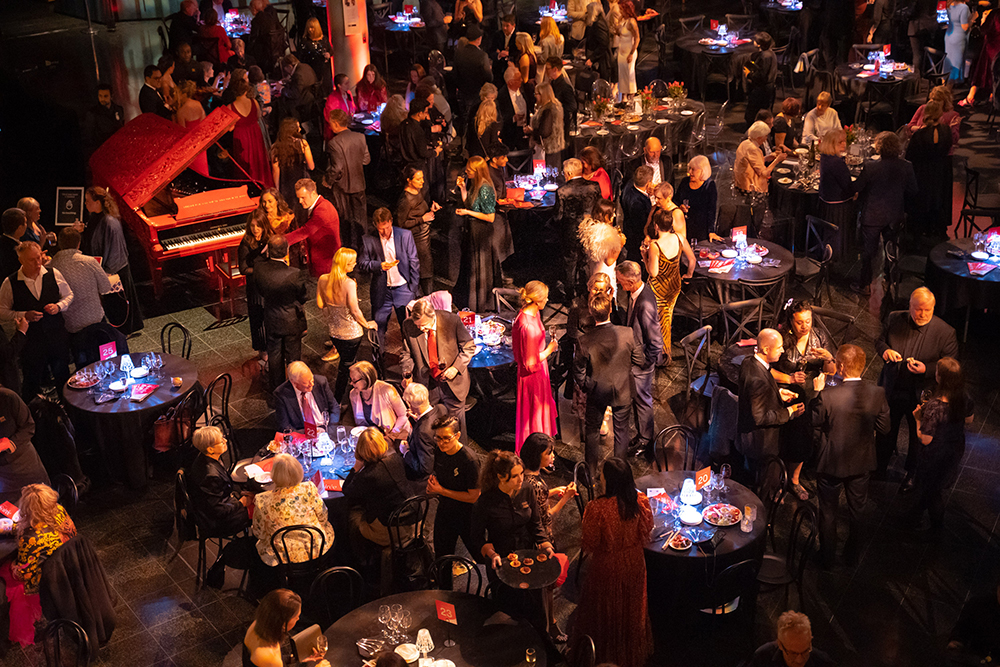 An aerial view of a crowd at an evening event in a large space.