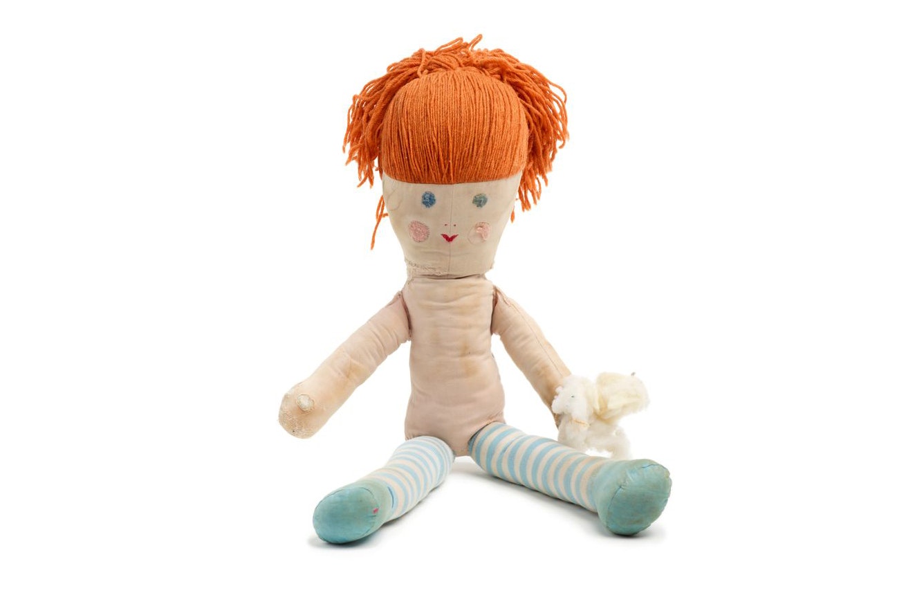 A rag doll with orange hair is sitting on a white background.
