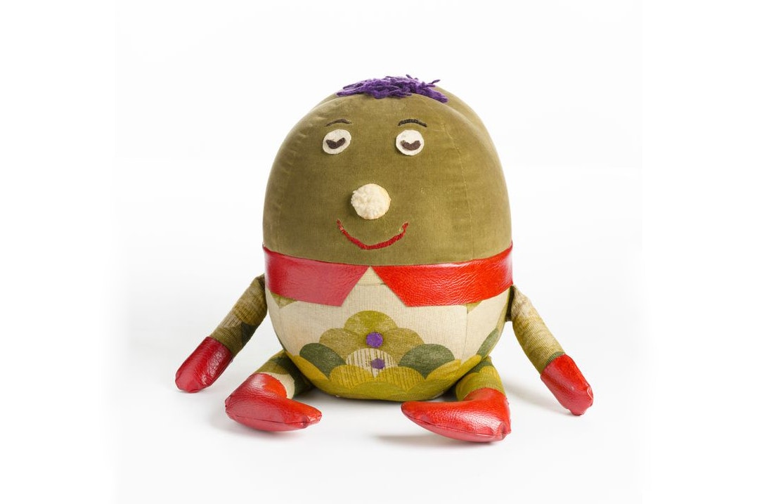 A stuffed round green egg-shaped toy wearing trousers.