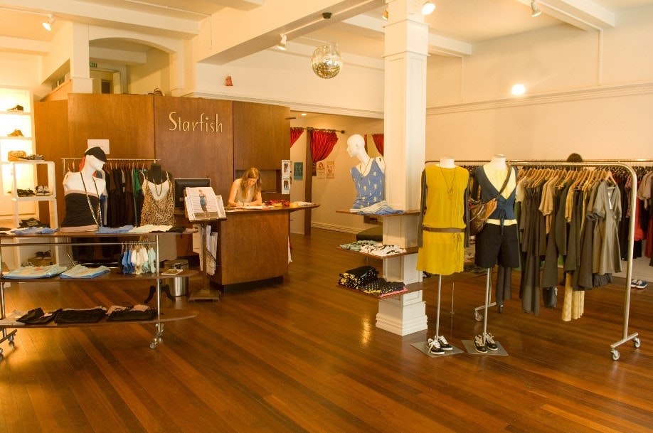 A woman is behind the counter of a clothing store.