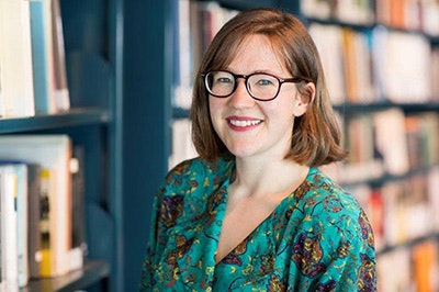 A head and shouldrs photo of a woman with brown hair and wearing glasses