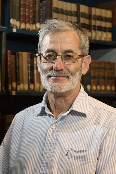 Head and shoulders of a man with a trim beard and glasses smiling sat the camera