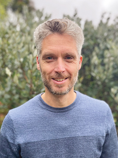 Head and shoulders of a man with short grey hair.