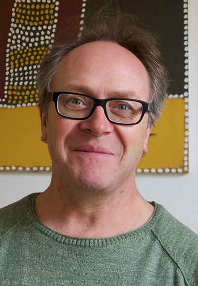 Head and shoulders of man wearing glasses looking at the camera.