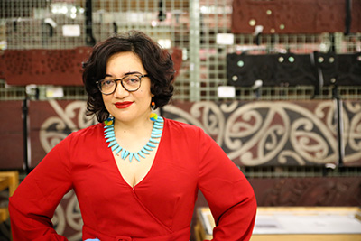 Head an shoulders of a woman in a red dress who is smiling at the camera