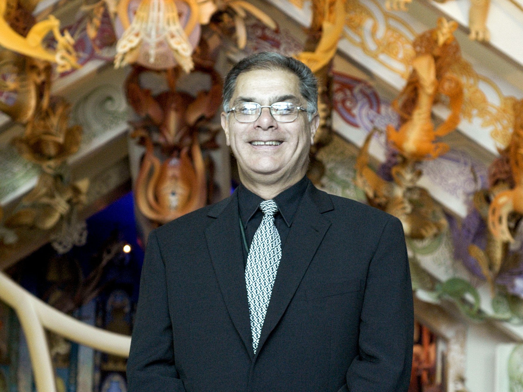 Jonathan Mane-Wheoki. Te Papa (87981) A head and shoulders photo of a man in a suit smiling at the camera.