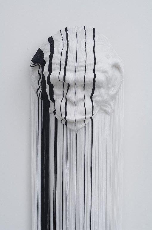 A white monkey face mask with black and white string hanging down from it