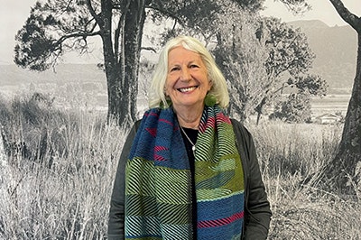 A photo of a woman with white shoulder-length hair. She is smiling at the camera.