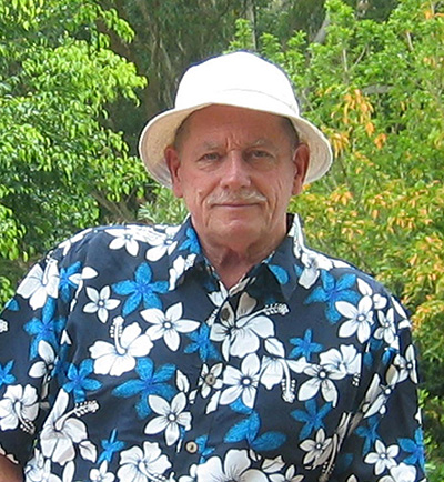 Head and shoulders of a man in a white hat and a blue and white flower shirt