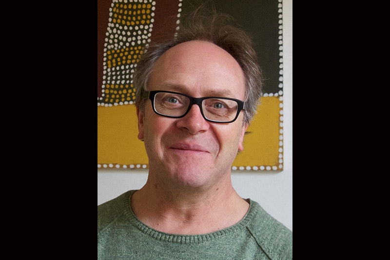 Head and shoulders of a man wearing glasses smiling at the camera