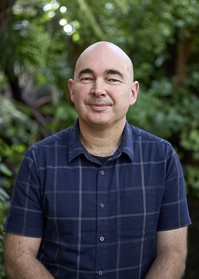 Head and shoulders photo of a man with no hair smiling at the camera.